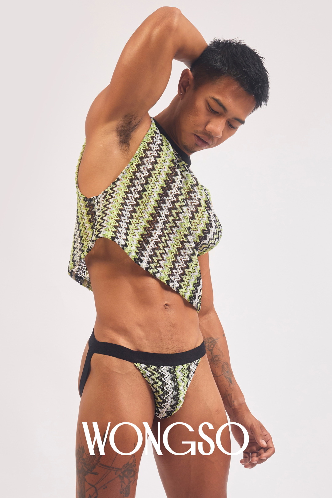Queer model in green knit crop top with arms raised