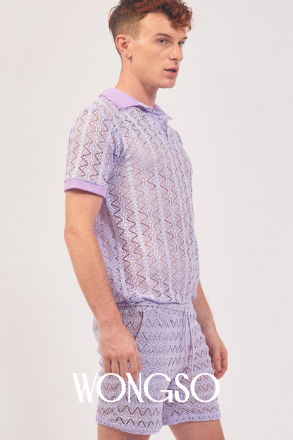 Queer man wearing lilac lace polo shirt styled with festival shorts – WONGSO men’s lacewear