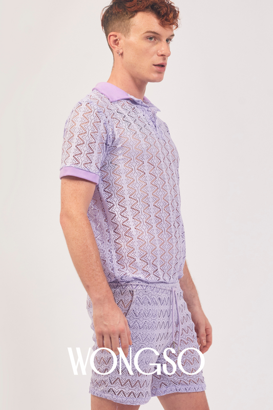 Queer man wearing lilac lace polo shirt styled with festival shorts – WONGSO men’s lacewear